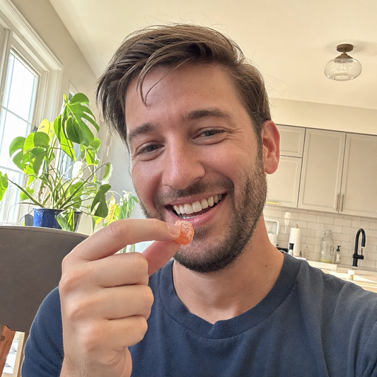 Man smiling taking a Bloom Clean probiotic gummy